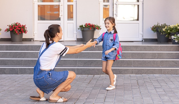 Een moeder begeleidt student naar school, gelukkig meisje met een zorgzame moeder, terug naar school.