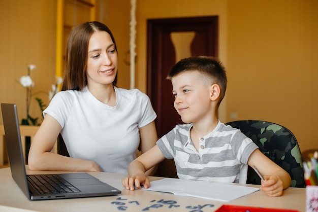 Een moeder en haar kind zijn thuis achter de computer bezig met afstandsonderwijs. Blijf thuis, training.