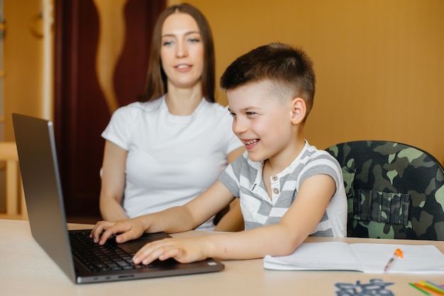 Een moeder en haar kind zijn thuis achter de computer bezig met afstandsonderwijs. Blijf thuis, training.