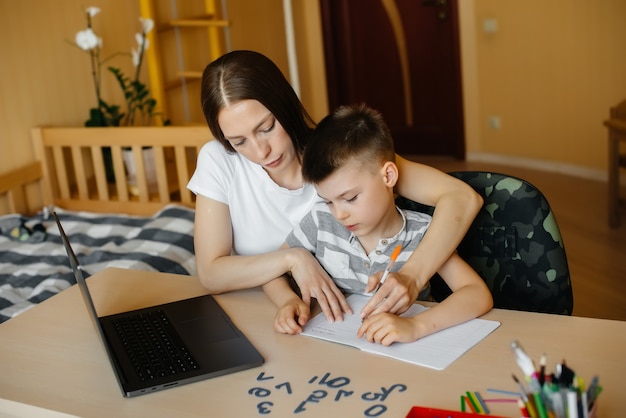 Een moeder en haar kind zijn thuis achter de computer bezig met afstandsonderwijs