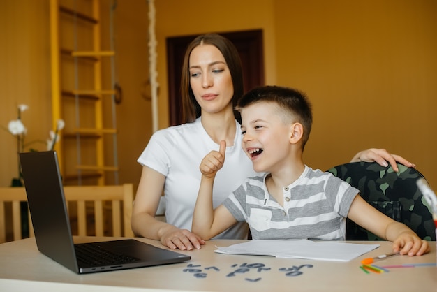 Een moeder en haar kind zijn thuis achter de computer bezig met afstandsonderwijs