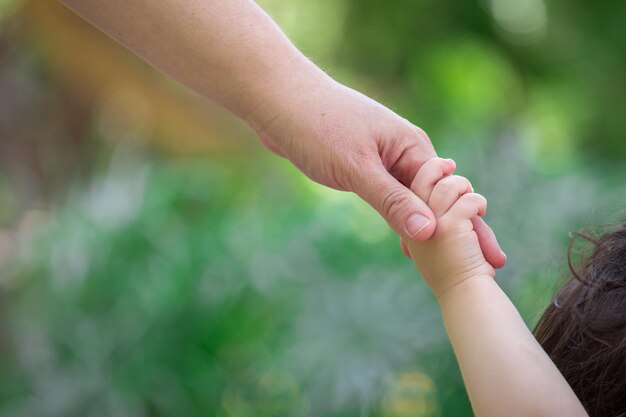 een moeder houdt haar baby's hand omhoog naar de hemel