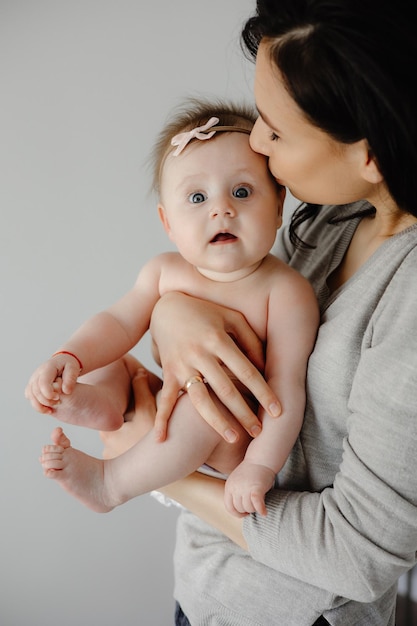 Een moeder kust haar babymeisje in haar armen.