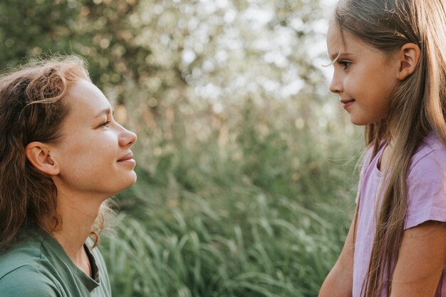 Een moeder met een klein intra-kanaal hoortoestel communiceert met haar dochtertje in de natuur buiten