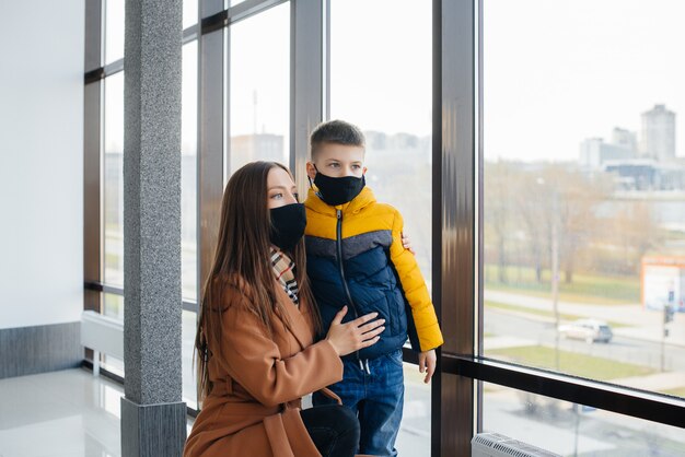 Een moeder met haar kind staat tijdens de quarantaine in een masker. Pandemie, coronavirus.