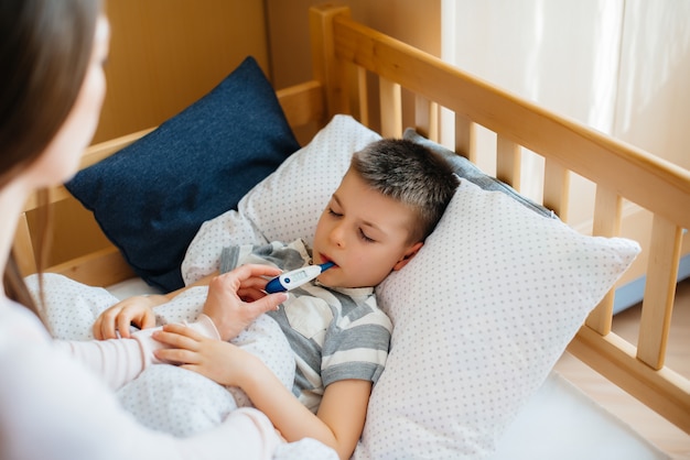 Een moeder zorgt voor haar kind met koorts en koorts. Covid19, coronavirus, pandemie.