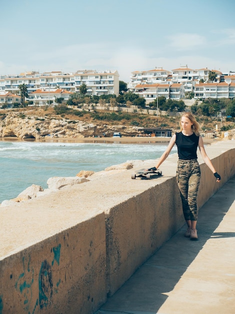 Een mooi blond meisje gaat op de pier en duwt de hand van de skate