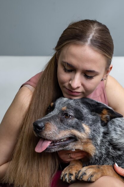 een mooi blond meisje zit op de bank en knuffelt een genezerhond