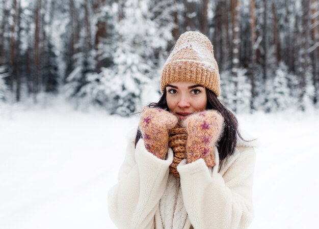 Een mooi gelukkig lachend jong meisje in handschoenen en een muts-sjaal, bedekt met sneeuwvlokken.