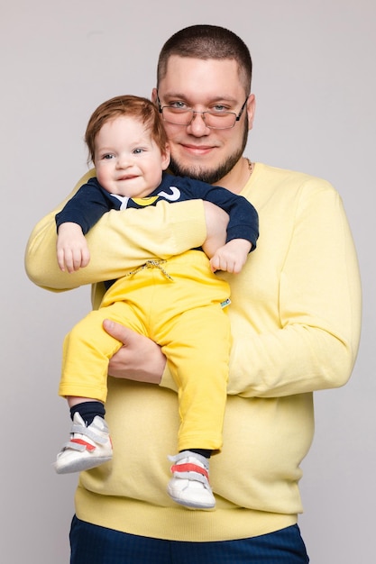 Een mooi gezin met een klein kind in de studio op een grijze achtergrond