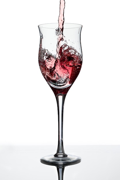 Een mooi glas serveren met een heerlijke rode wijn. Witte achtergrond, glazen beker. Elegantie, goede smaak, stijlconcept.