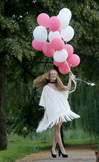 Foto een mooi jong meisje houdt veel kleurrijke ballonnen in de lucht