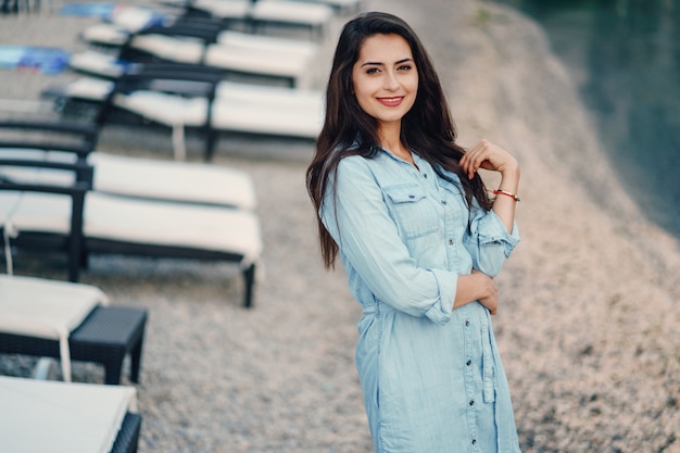 Een mooi jong meisje in een blauwe kleding die zich dichtbij water bevindt