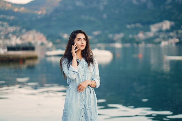 Een mooi jong meisje in een blauwe kleding die zich dichtbij water bevindt