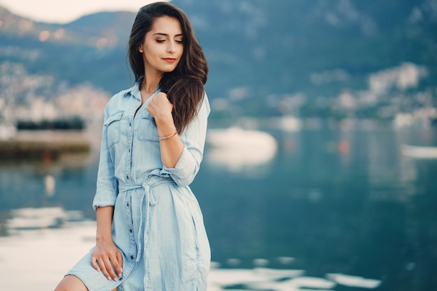 Een mooi jong meisje in een blauwe kleding die zich dichtbij water bevindt