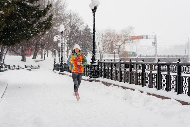 Een mooi jong meisje is joggen op een ijzige en besneeuwde dag. Sport, gezonde levensstijl