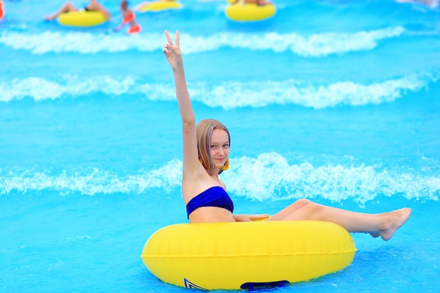 Foto een mooi jong meisje ligt op een opblaasbare matras in het zomer-waterpark. meisje zwemt in het zomerzwembad.
