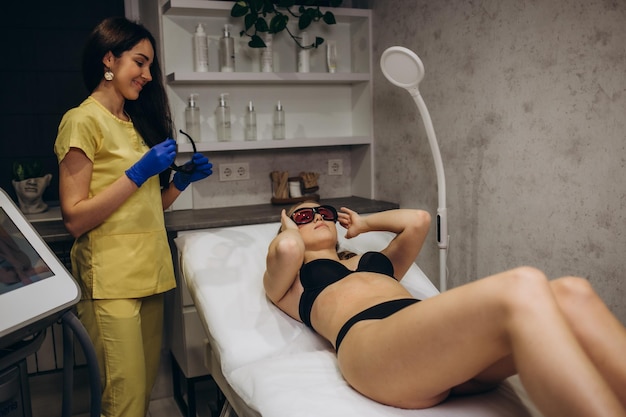Een mooi jong meisje zal laser ontharing ondergaan met moderne apparatuur in een spa salon