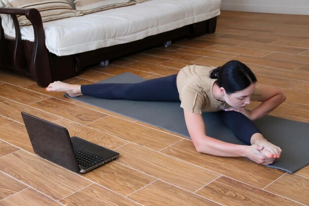 Een mooi jong sportmeisje in een legging en een topje gaat sporten thuisSport online thuis