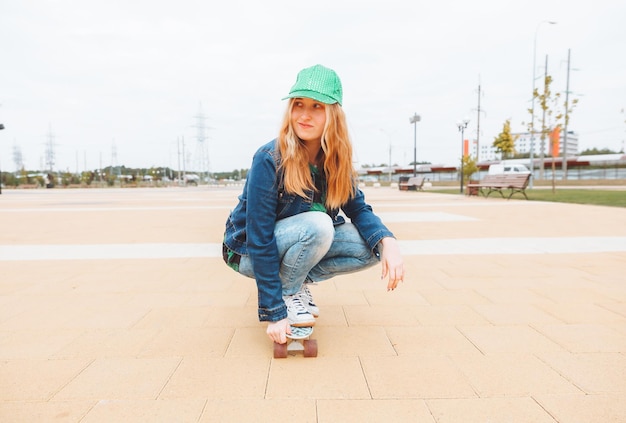 Een mooi jong tienermeisje rijdt op een skateboard bij zonnig weer generatie z