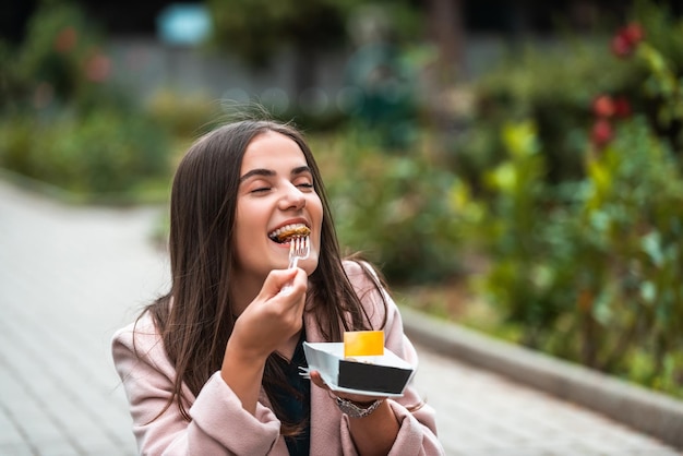 Een mooi lachend meisje eet verse poffertjes terwijl ze door de stad toert Selectieve focus