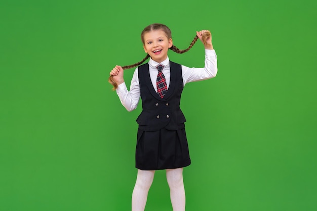 Een mooi lachend schoolmeisje houdt haar staartjes vast. het meisje houdt van school. geïsoleerde achtergrond. het schoolcurriculum bestuderen, verlangen naar kennis op school.