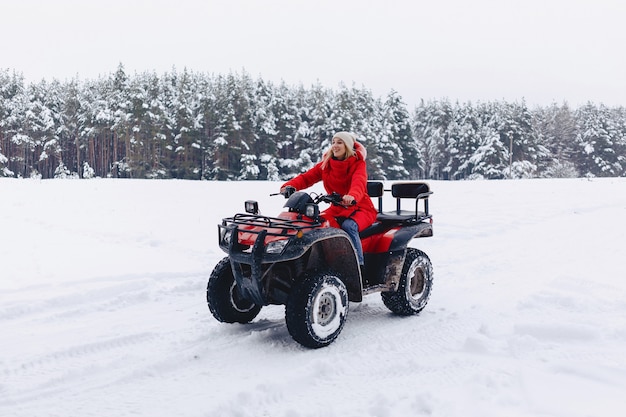 Een mooi meisje dat een quadrocycle berijdt op een schilderachtig sneeuwgebied