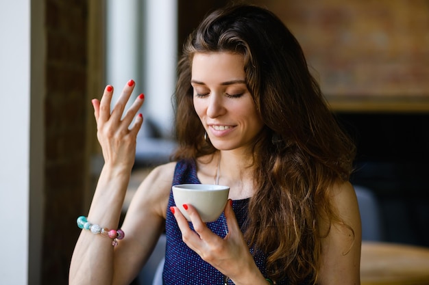 Een mooi meisje drinkt thee en geniet van de geur en smaak