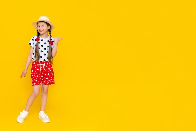 Een mooi meisje gekleed in zomerkleren rode polka dot korte broek een plek om te kopiëren op een gele achtergrond