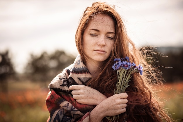 Een mooi meisje geniet van de geur van een boeket korenbloemen.