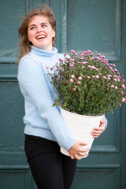 Een mooi meisje houdt een groot boeket bloemen vast en lacht Gelukkige jonge vrouw in de stad