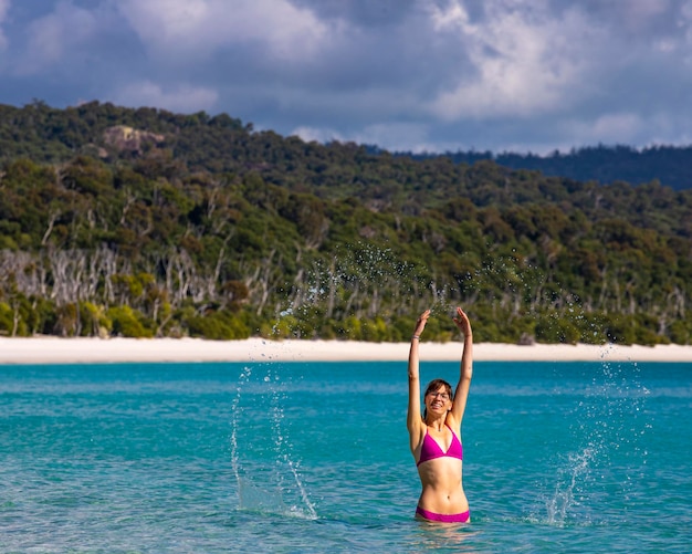 Een mooi meisje in een bikini geniet van een duik in het turquoise water op Whitehaven Beach, Australië