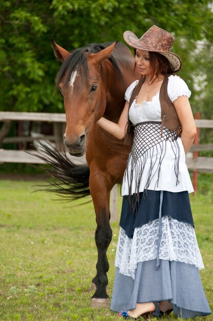 Een mooi meisje in een cowboyhoed met een paard