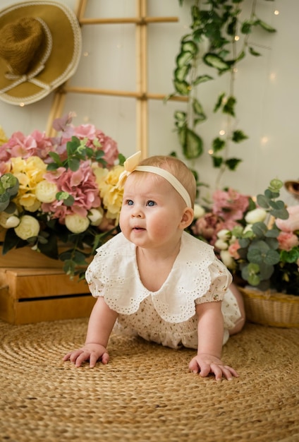 Een mooi meisje in een gekleurd rompertje met een hoofdband kruipt op het tapijt tussen bloembakken