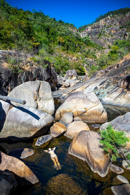 een mooi meisje in een witte bikini ligt op het water in een natuurlijk zwembad in jourama Falls, Australië