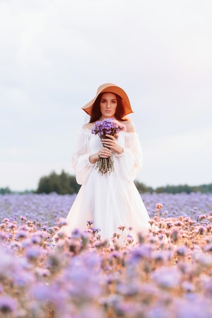 Een mooi meisje in een witte jurk in een bloeiend gebied van de Provence in een romantische sfeer