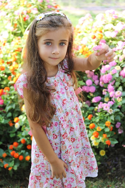 een mooi meisje met bruin haar en lichtgroene ogen, blij en glimlachend met twee bloemen