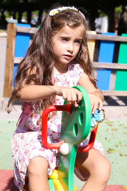 een mooi meisje met bruin haar en lichtgroene ogen, gelukkig en glimlachend op een schommel in Alicante