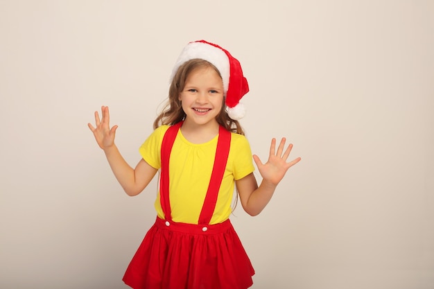 een mooi meisje met een kerstmuts in een rode rok en een geel T-shirt lacht naar het nieuwe jaar