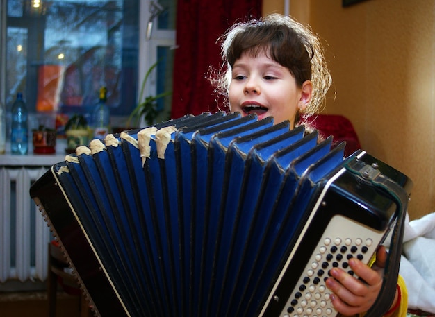 Foto een mooi meisje zingt en speelt een oude accordeon. het portret van kinderen.