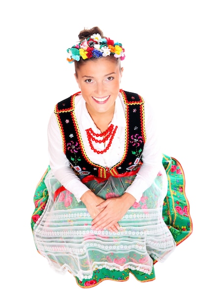 een mooi Pools meisje in traditionele kleding zittend op een witte achtergrond
