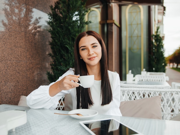 Een mooi schattig meisje in een café drinkt koffie aan een tafel.
