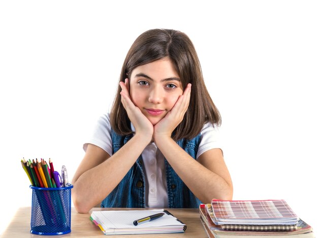 Een mooi schoolmeisje zit aan het bureau en denkt Wit