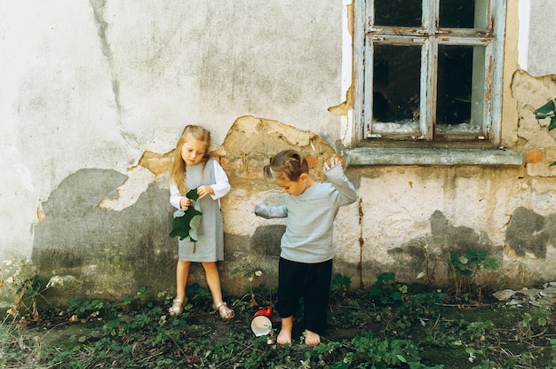 Foto een mooi stel kinderen in grijze pakken speelt tegen de achtergrond van de muur