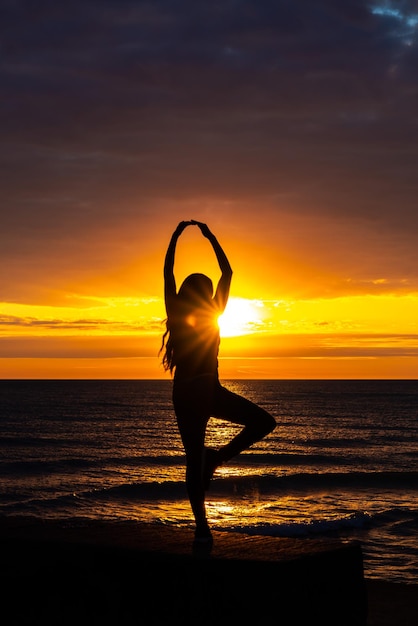 Foto een mooie afro-amerikaanse vrouw doet een ballerina pose creëert zonsopgang silhouet op het meer