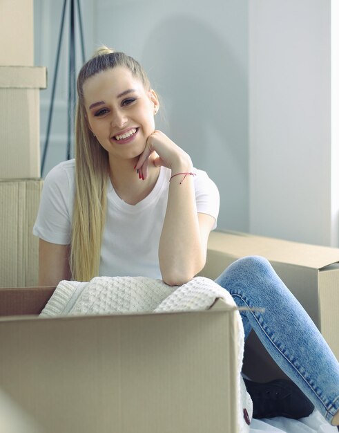Een mooie alleenstaande jonge vrouw die dozen uitpakt en naar een nieuw huis verhuist