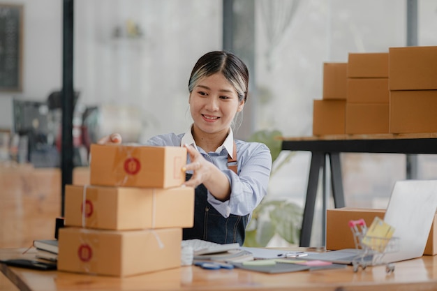 Een mooie Aziatische bedrijfseigenaar opent een online winkel, ze controleert bestellingen van klanten die goederen verzenden via een koeriersbedrijf concept van een vrouw die een online bedrijf opent