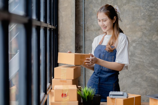 Een mooie Aziatische bedrijfseigenaar opent een online winkel, ze controleert bestellingen van klanten die goederen verzenden via een koeriersbedrijf concept van een vrouw die een online bedrijf opent