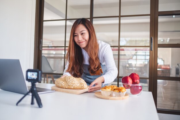 Een mooie Aziatische foodblogger of vlogger die een video op camera opneemt