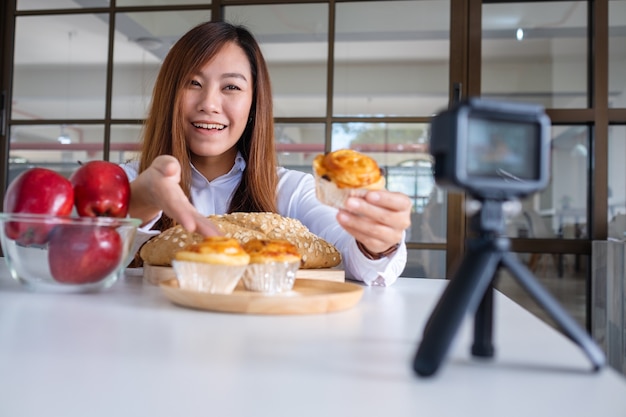 Een mooie Aziatische foodblogger of vlogger die een video op camera opneemt